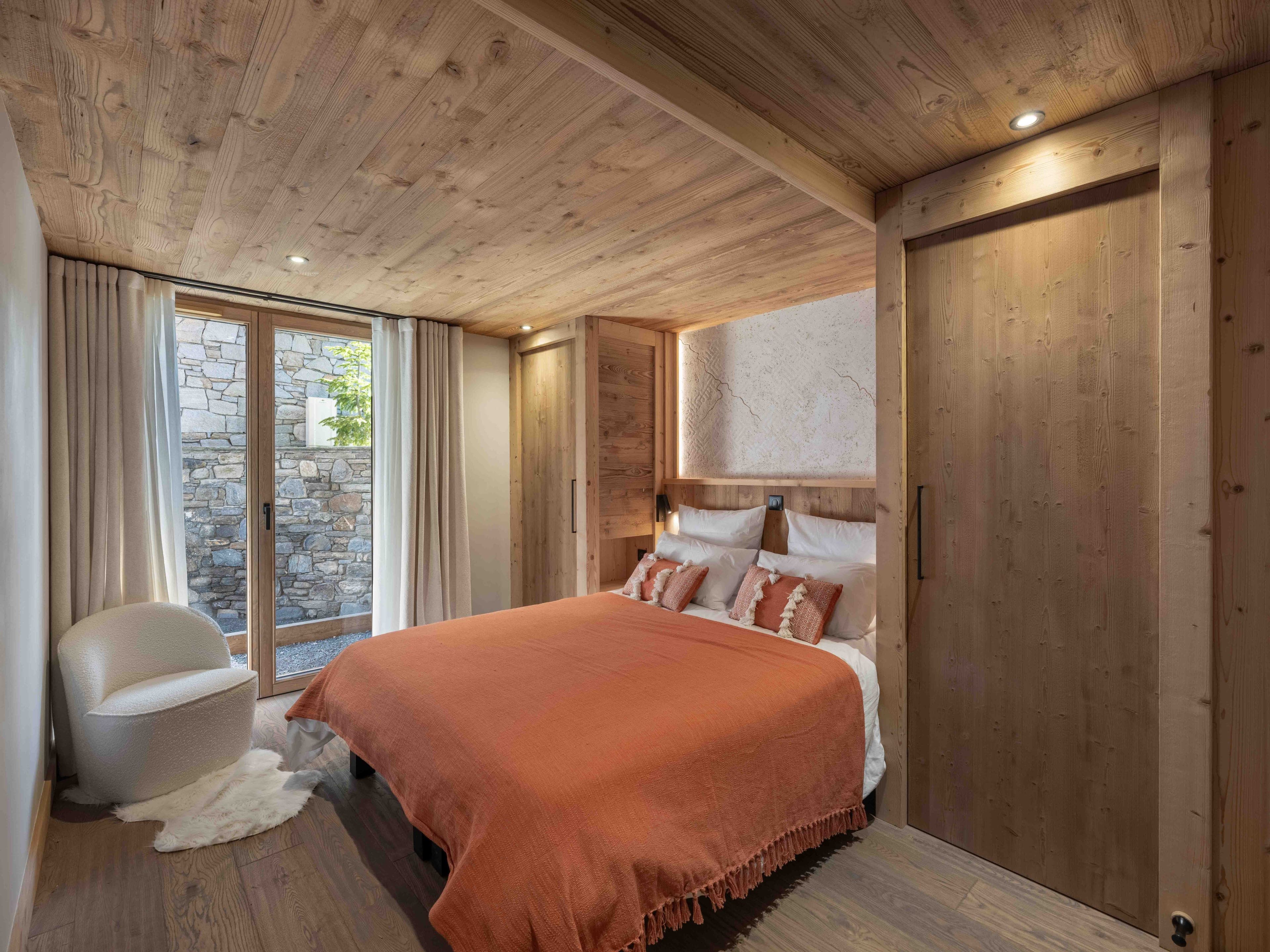 Double bedroom with a terracotta throw and white armchair